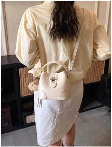Detail of cream white leather bucket bag with silver twist lock and cute teddy bear charm