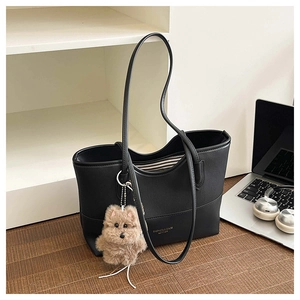 Dettaglio della borsa tote in pelle nera con fodera a righe e ciondolo a forma di peluche