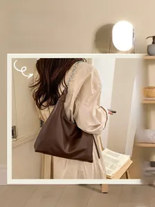 Detail of dark brown glossy leather tote bag with chunky silver metal chain strap