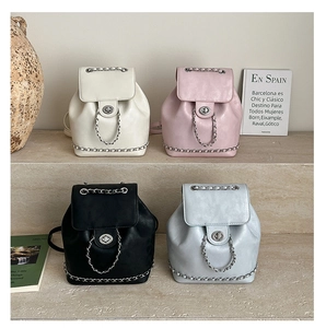 Close-up of four colored leather backpacks featuring silver metal locks and chain details