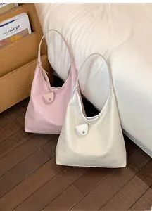 Detail view of pink and beige oversized hobo bags with matching mini pouches on floor