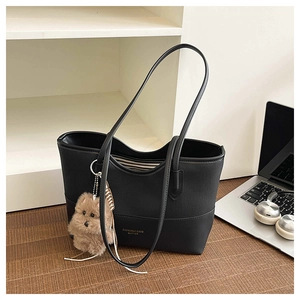 Dettaglio macro della borsa tote in pelle nera con texture miste e un simpatico ciondolo peluche
