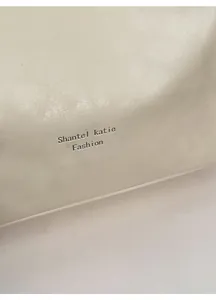 Close-up of soft beige leather texture with black logo detail on slouchy tote bag