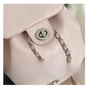 Close-up of light pink pebble leather backpack with silver metal turn-lock and chain detail