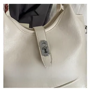 Gros plan détaillé d'un sac seau en cuir crème avec un fermoir argenté en forme de lame