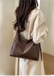 Detail showing the deep brown leather texture and wide strap of the large tote bag