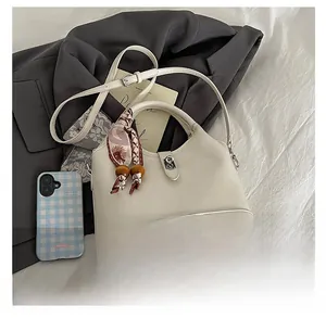 Détail du sac seau blanc cassé avec fermoir rotatif argenté et foulard à fleurs