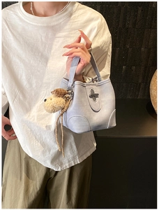 Detail of light blue bucket bag with metal twist lock and cute plush dog charm
