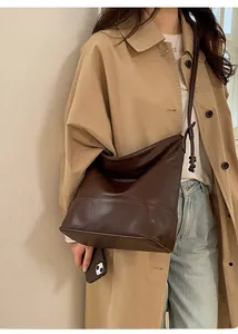 Detail of a large dark coffee shoulder bag featuring an adjustable knotted strap design