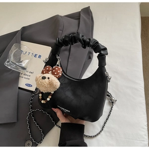 Detail of black crescent crossbody bag with scrunchie handle and plush bear charm