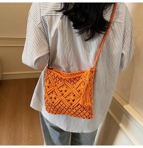 Close-up of bright orange macrame woven bag with geometric patterns and long side tassels