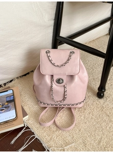 Detail view of pink PU leather backpack with silver rotating lock and chain strap accents