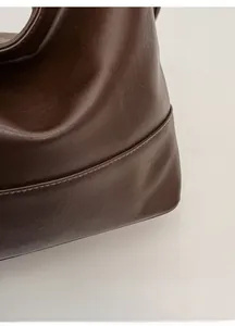 Close-up of the fine leather texture and precise edge stitching on the brown shoulder bag