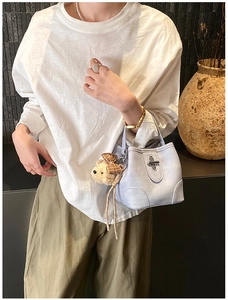 Detail of light blue bucket bag with metal turn-lock and plush bear pendant accessory