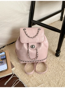 Detail of pink leather backpack featuring silver twist lock and chic metal chain trim design