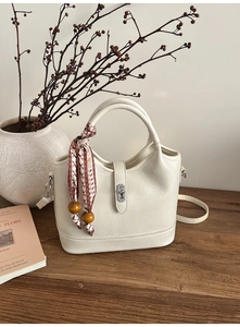 Détail d'un sac seau beige avec foulard en soie à motifs et perles rondes en bois