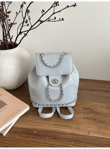 Detailed close-up of light blue leather backpack with silver chain accents and oval lock