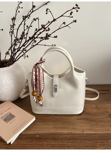 Détail du sac seau crème avec fermoir rotatif argenté et poignée en foulard de soie