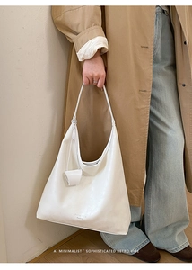 Detailed view of large white leather tote bag with knotted charm and minimalist design