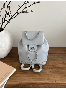 Detail of light blue chain backpack with silver metallic lock on dark wood surface
