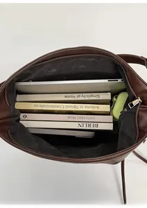 Top-down close-up of spacious interior with laptop and books in dark brown leather tote