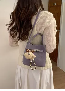 Detail of purple leather bucket bag with silver twist lock and cute bear pendant charm