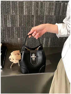 Close-up of black leather bucket bag featuring silver twist lock and teddy bear charm