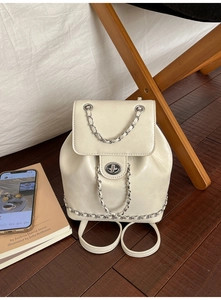 Detail of a creamy white mini backpack featuring a silver chain strap and metal swivel lock