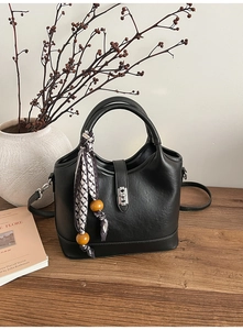 Détail du sac seau en cuir noir texturé avec fermoir argenté et foulard géométrique