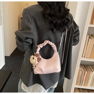 Detail of pink dumpling bag with pleated handle, chain strap and cute bear charm