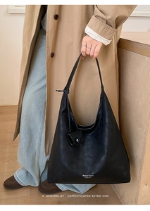 Detail of minimalist black leather oversized hobo tote bag with branding and wide strap
