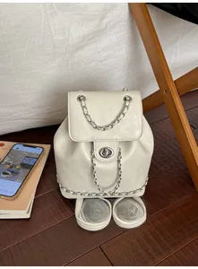Detailed view of beige leather backpack featuring silver chain accents and twist lock closure