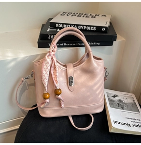 Détail d'un sac seau rose clair avec foulard décoratif et fermoir rotatif en métal