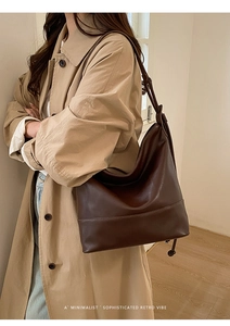 Brown retro hobo bag with adjustable shoulder strap worn by a model in a minimal interior