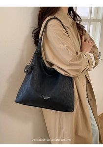 Detail of minimalist black leather hobo bag with white branding and soft texture