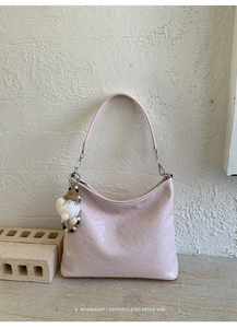 Dettaglio della borsa sottobraccio in pelle rosa chiaro increspata con ciondolo gnomo