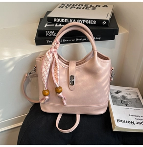 Détail du sac seau rose clair avec poignée en foulard de soie et breloques en bois