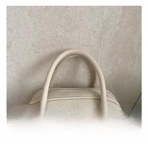 Close-up of padded top handles and silver metal rings on a beige pebbled leather bag