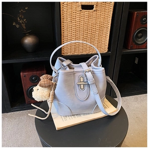 Detail of light blue bucket bag with silver clasp and cute plush dog charm on a book