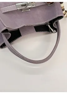 Detail view of purple lychee pattern leather bag with silver twist lock and wide handle