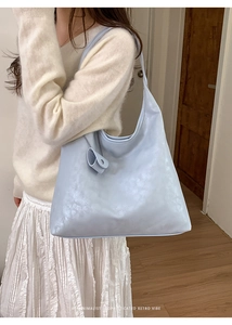 Detail of light blue patent leather tote bag showing textured surface and side view
