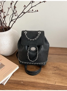 Detailed view of black matte backpack with silver metal chain decor and twist lock