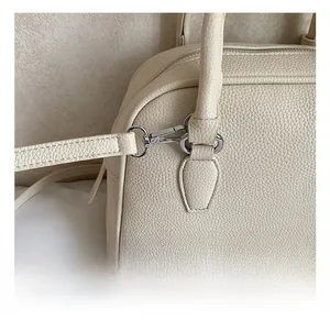 Detail of silver metal hook and fine stitching on a creamy white leather bowling bag