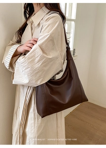 Detail view of large dark brown retro leather tote bag worn on shoulder by model