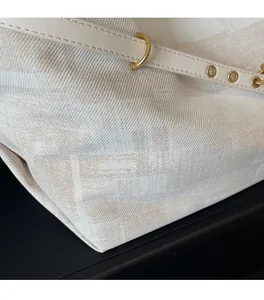 Close-up of beige jacquard tote bag featuring premium metal eyelets and leather strap