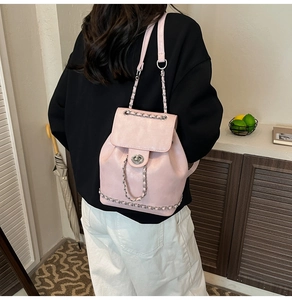 Detailed back view of a pink faux leather backpack with silver chain straps on a model