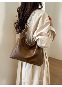 Detail of a brown shoulder bag with a silver chain strap showing the retro textured material