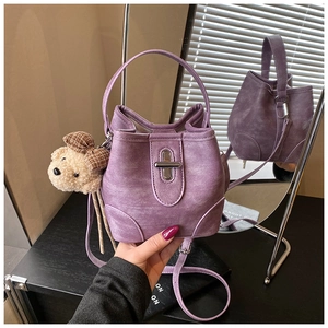 Detail of purple suede bucket bag featuring metallic lock and cute teddy bear pendant