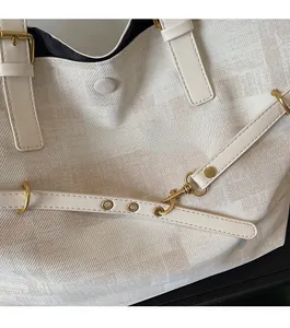 Detail of canvas tote bag showing the cream white jacquard pattern and gold metal hardware