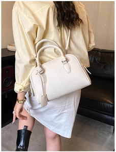 White litchi grain leather Boston bag worn crossbody with silver hardware and tag detail
